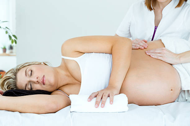 Femme enceinte couchée sur le coté recevant un massage